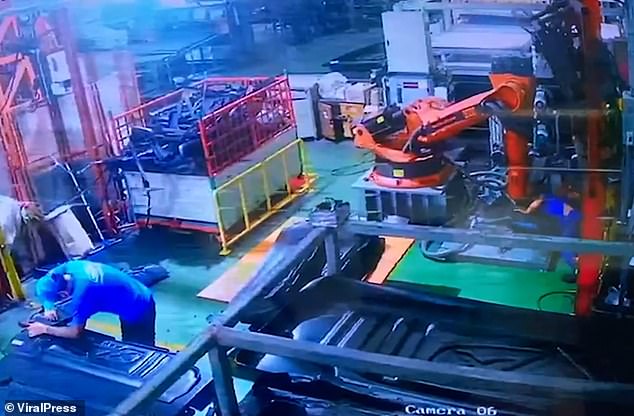 Disturbing CCTV footage shows how the victim was left incapacitated under the huge metal device as a colleague continued to work across the room, seemingly oblivious to the disaster unfolding just behind him.