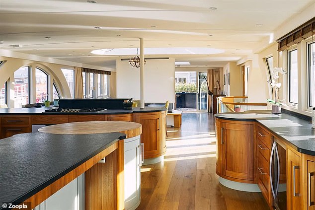 The smart kitchen has curved cabinets, a large central island and views of the Thames