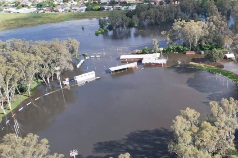 A country football field from the air. It is under water and the buildings around it are submerged