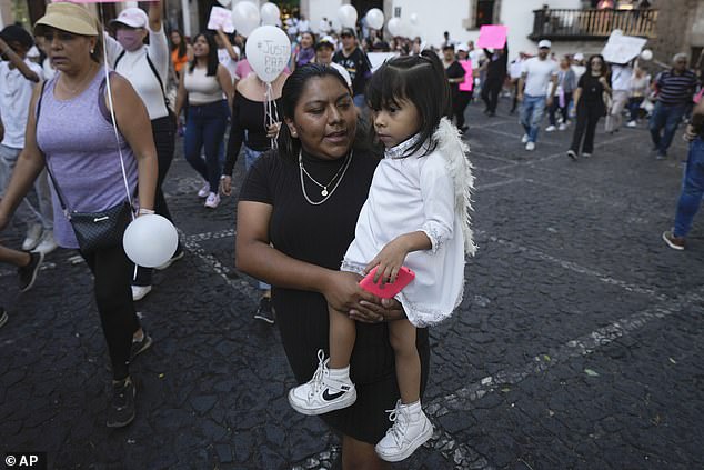 A woman carries her daughter during a demonstration protesting the kidnapping and murder of an 8-year-old girl in the main square of Taxco, Mexico, on Thursday.