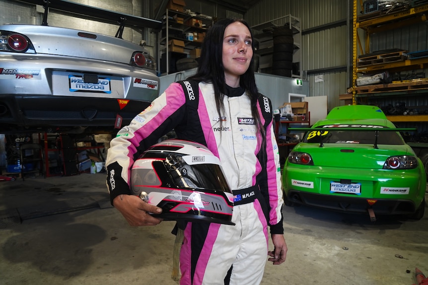 Motorsports driver Maisie Place in her racing suit in her garage in Moruya. 