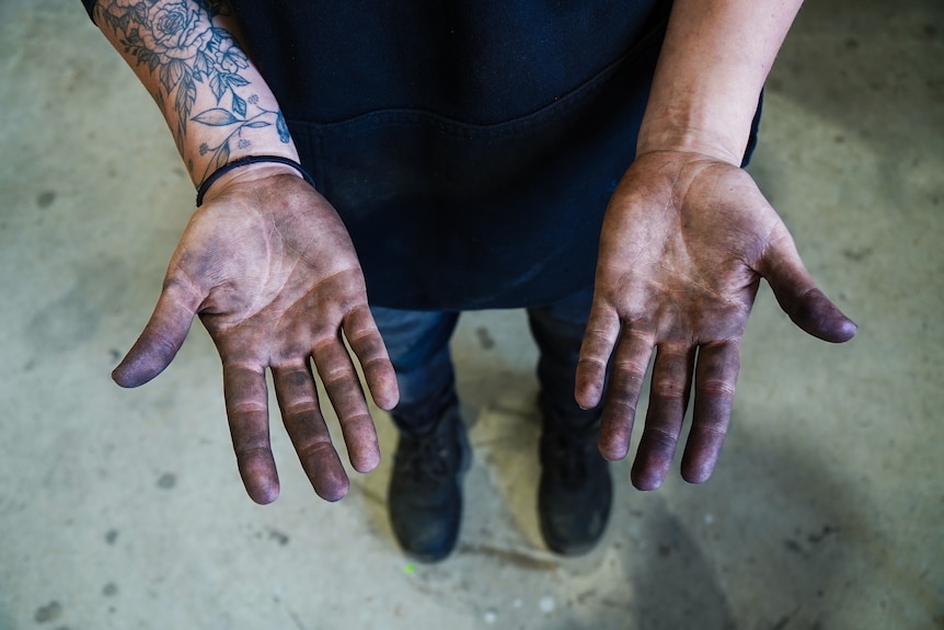 A woman's hands covered in black grease and motor oil.