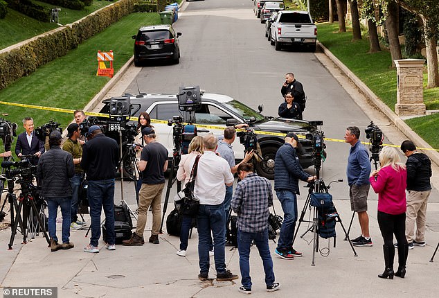 Members of the media work as law enforcement officers stand behind police tape at Diddy's home in Holmby Hills.