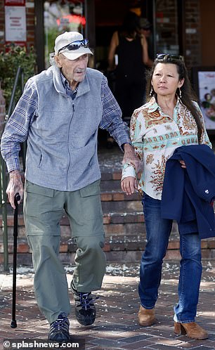The retired actor was seen holding onto his wife for balance.