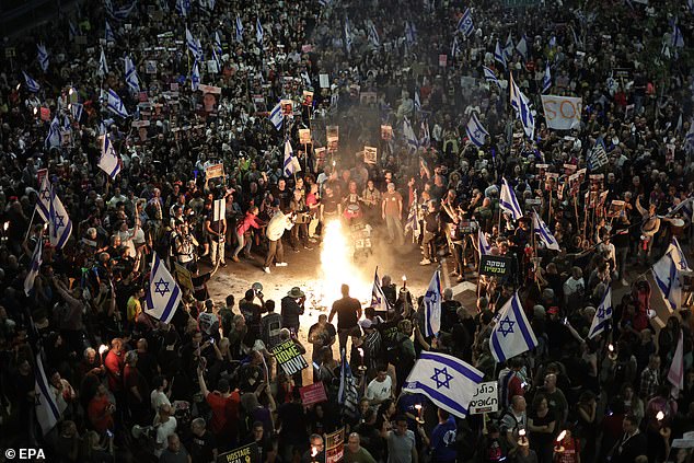 Relatives and supporters of Israeli hostages held by Hamas in Gaza, carrying Israeli signs and flags, lit a bonfire during a demonstration in front of the Kirya military headquarters.