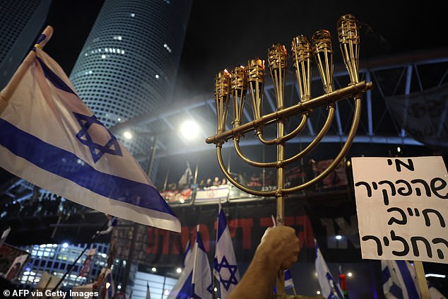A protester carries a menorah during a meeting of relatives of Israeli hostages.