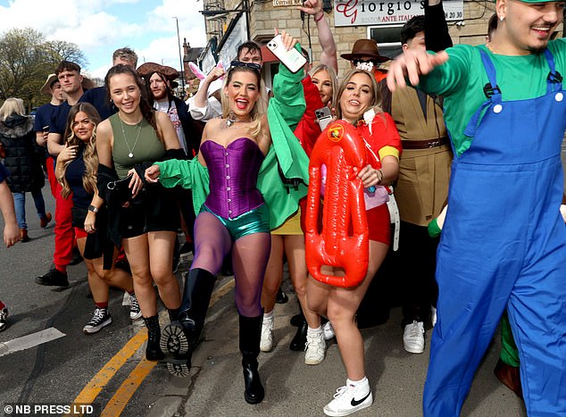 A man is dressed as Luigi from Mario Bros, followed by a woman dressed in a Baywatch costume and another girl dressed in a corset and green shorts. In the background, a man dressed as a pirate and you can see rabbit ears poking out.