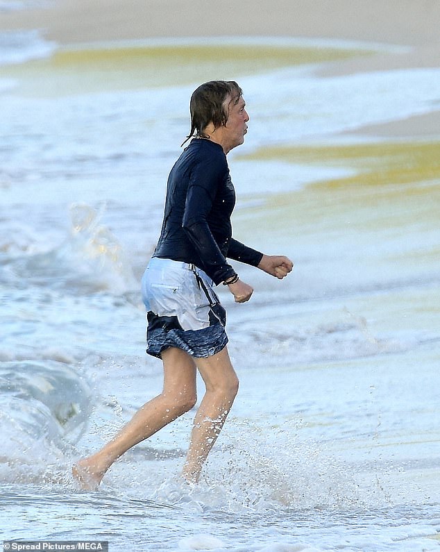 Wearing colorful swim shorts and a navy long-sleeved T-shirt, Paul looked incredibly relaxed as he frolicked in the ocean.