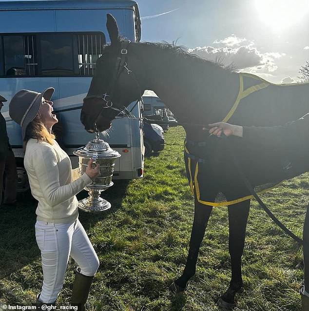 Geri smiles and holds a trophy in front of her horse Lift Me Up after winning a race on Easter Saturday.