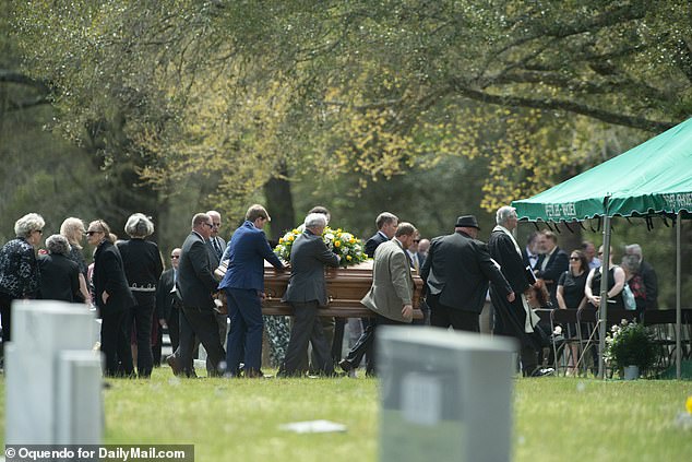 Exclusive pictures obtained by DailyMail.com show more than a hundred mourners attended the funeral in the family plot at Hampton Cemetery.