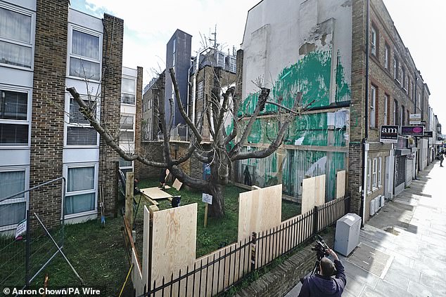 Plastic screens and wooden fencing have been put up over Banksy's latest mural on the side of a block of flats in Islington.