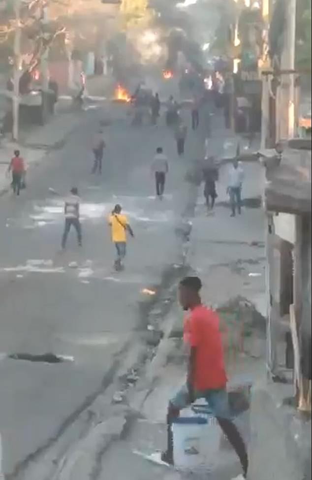 Haitians are seen carrying buckets of water against the fire as official authorities remain largely absent during the ongoing crisis
