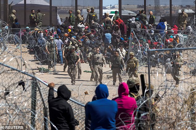 Illegal migrants pass through barbed wire as they forcibly enter the United States across the southern border on March 21, 2024.