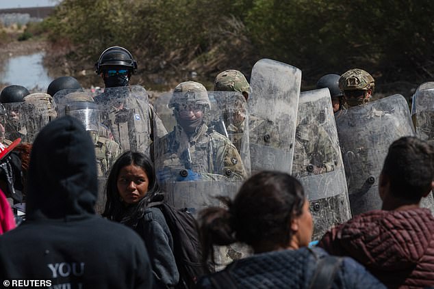 Texas State Police stand guard blocking migrants camped along the riverbank at the US-Mexico border near El Paso, Texas.
