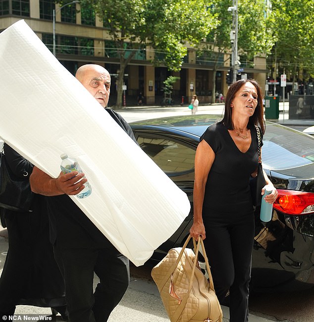 Aggie Di Mauro and Tony, Celeste's father, enter the Supreme Court of Victoria on Thursday carrying their daughter's ashes under a white blanket.