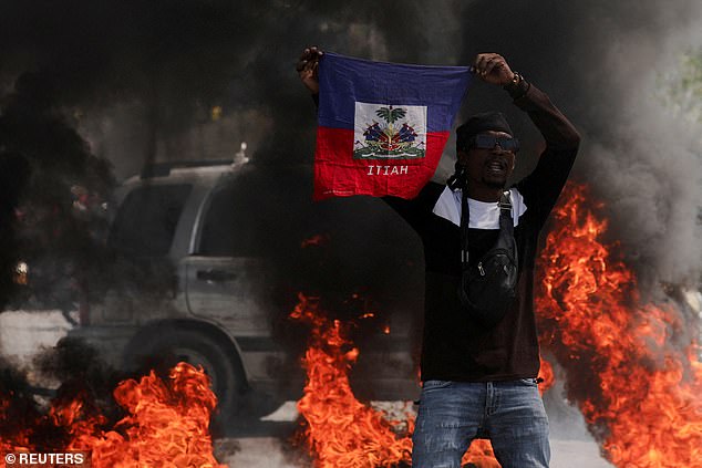 A protester holds the Haitian flag during protests against the country's prime minister.
