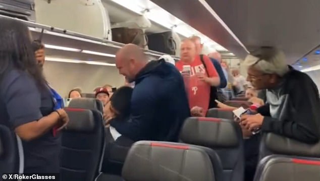 An unruly American Airlines passenger was strangled by another passenger before being escorted off the plane.  (in the photo: the disruptive flyer in a chokehold)