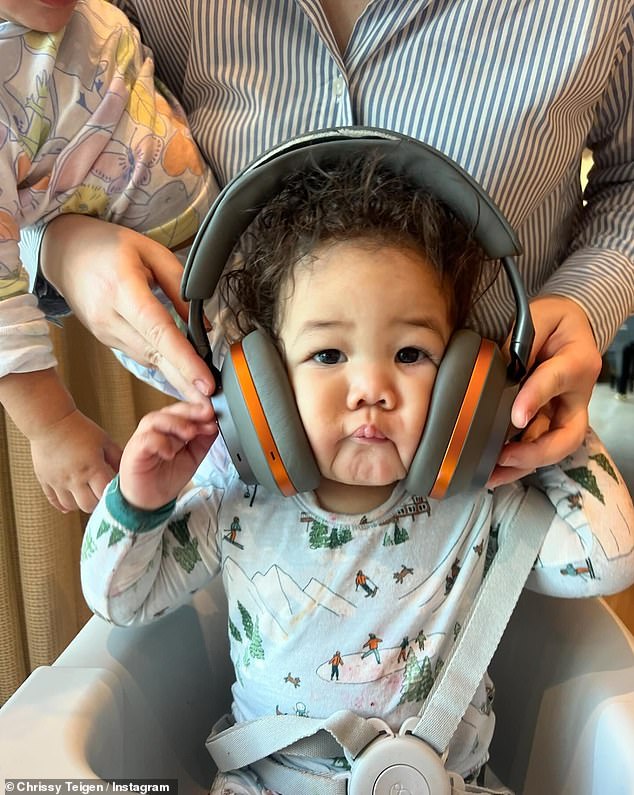 Next, Teigen's little one-year-old daughter Esti was caught with a pair of large headphones squishing her cheeks while strapped in her high chair.