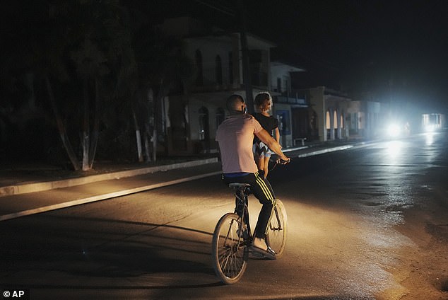 A man pedals a bicycle carrying a girl during a planned power outage in Bauta, Cuba, on Monday.
