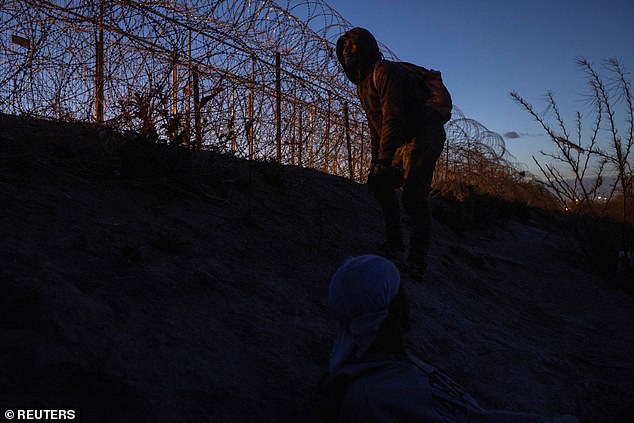 A migrant seeks to breach a heavily fortified barbed wire fence from the bank of the Rio Grande in El Paso, Texas, US, March 24.