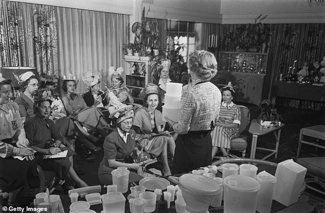 A group of unspecified women attend a Tupperware party, some wearing hats made from Tupperware products, circa 1955.