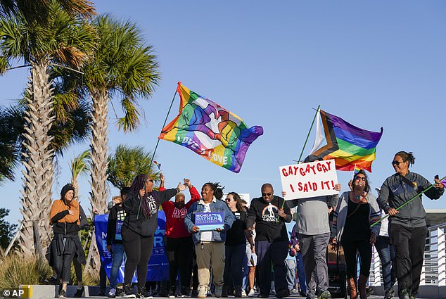 Marchers wave flags as they walk on St. Pete Pier during a protest against the 'Don't Say Gay' bill in March 2022