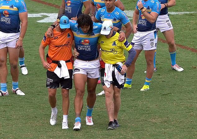 Gold Coast captain Tino Fa'asuamaleaui is being helped off the field after injuring his knee against the Bulldogs