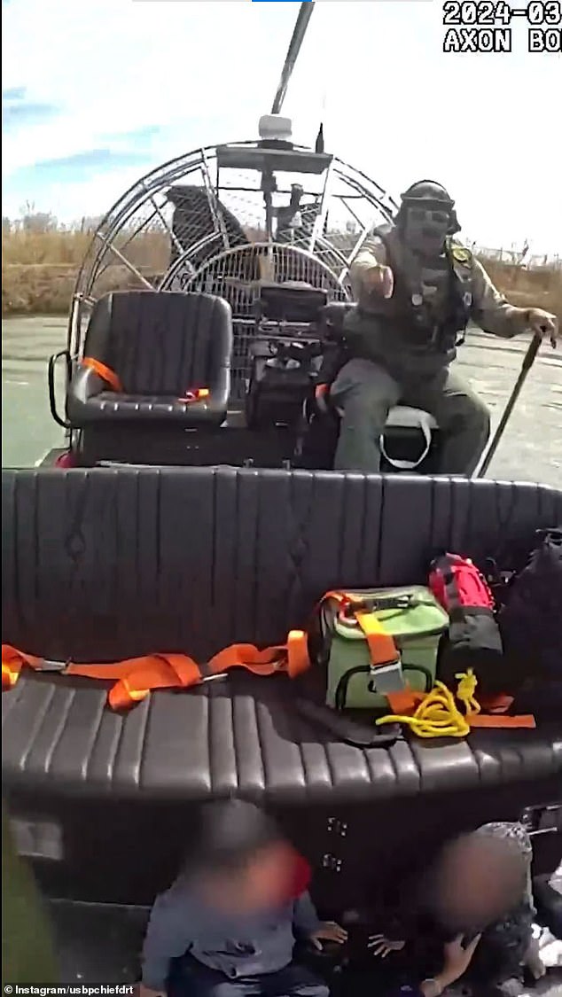 Two young children, a boy and a girl, can be seen sitting on the Border Patrol airboat after being taken out of the dangerous river.