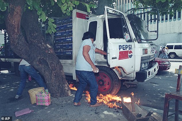 A Pepsi-Cola delivery truck driver in Manila tries to put out the fire under his truck after it was set ablaze by protesters in September 1993. Such demonstrations were common that year, after an incident involving a new promotion.