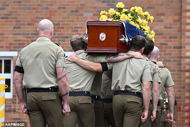 Arm in arm, pallbearers carry Lance Corporal Fitzgibbon's coffin into St. Joseph's Catholic Church Monday morning.