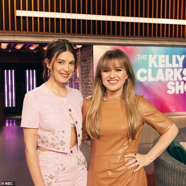 Kelly Clarkson looked svelte in a buttery yellow leather dress with leopard print heels during her talk show on Wednesday when she spoke to Millie Bobby Brown.