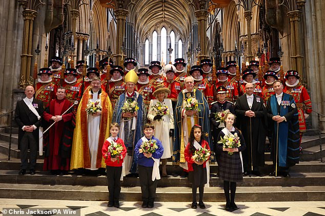 Queen Camilla holds the Nosegay bouquet as she poses with Yeomen of the Guard and religious representatives during the Royal Maundy service at Worcester Cathedral today.