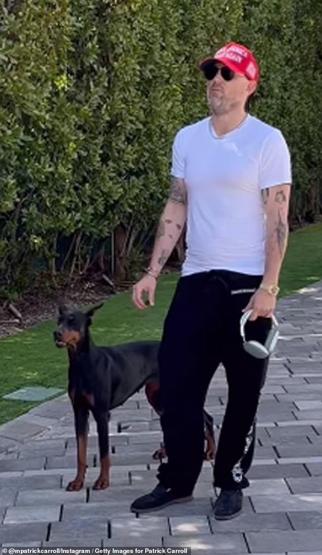 Patrick Carroll pictured in the driveway of his ultra-luxury home with one of his dogs as four police cars pull up outside his home