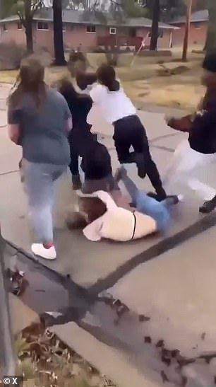 The victim then appears to have a seizure as other teenagers continue to fight over her body
