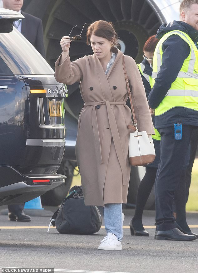Eugenie looked effortlessly chic in a camel double-breasted coat, blue plaid shirt and jeans after disembarking from the flight.