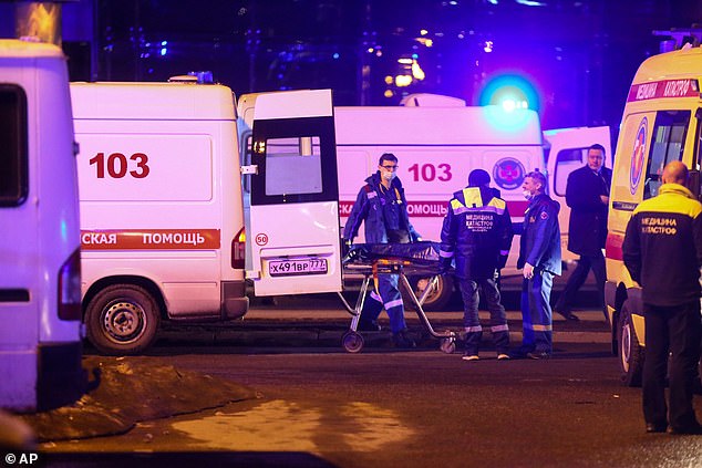 Doctors transport a body of a victim, a waiting ambulance near the burning building to the Crocus City Hall on the western outskirts of Moscow