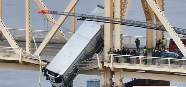 A large truck crashed into the side of an Indiana bridge, leaving the driver dangling dangerously from the side