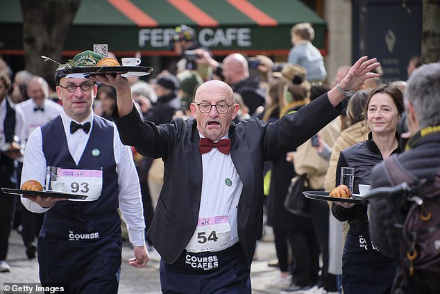 A waiter participating in the Course Des Café or Cafe Waiters' Race.  The first race began more than a hundred years ago, in 1914, and in it almost 300 Parisian waiters, dressed in their work clothes, travel 1.2 miles to and from the city hall of the French capital on the banks of the Seine River.
