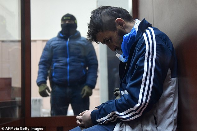 A man sits in the defendant's cage as he waits for his remand hearing at the Basmanny District Court in Moscow.