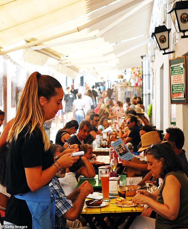 The file photo shows a waitress taking an order from a pad on the terrace of a tapas bar in Conil de la Frontera, near Cádiz, during a busy lunch hour.