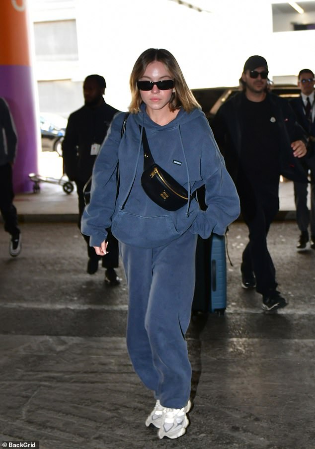 Sydney Sweeney took it easy on Monday as she jetted out of LA with her fiance Jonathan Davino.  The 26-year-old Euphoria star looked casual and comfortable in a gray and blue Miu Miu sweater as she stepped into LAX airport