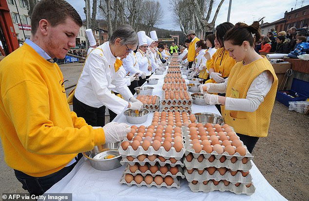 About 50 volunteers work together to make the giant omelet, breaking eggs and stirring the large frying pan.
