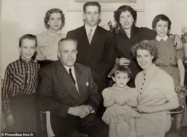 The little girl with a pudding bowl hairstyle sitting on her mother's knee is Brigitte Trogneux and on the far left is her brother Jean-Michel