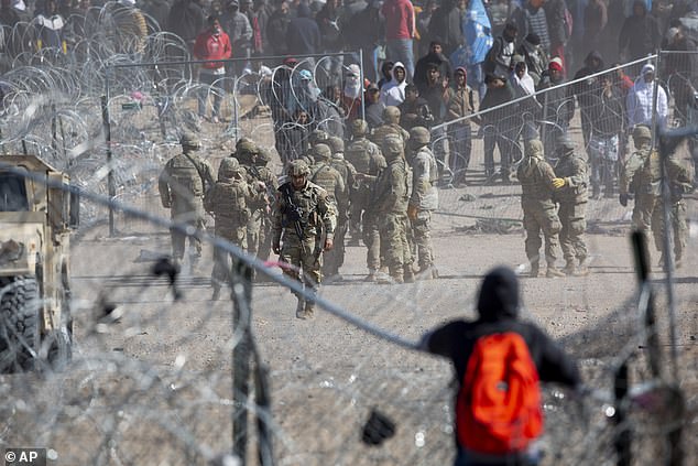 A migrant watches others breach concertina wire in the Rio Grande in El Paso, Texas, on Thursday, March 21, 2024. The migrants were awaiting processing by Border Patrol.