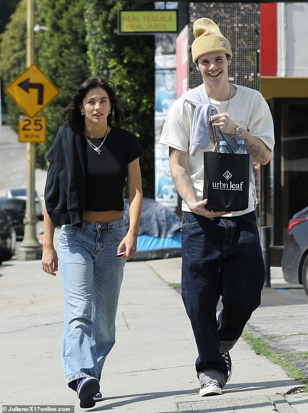 The son of David and Victoria Beckham, 19, looked in good spirits as he strolled along Sunset Boulevard with Skye, 23, on Thursday while holding a weed dispensing bag.