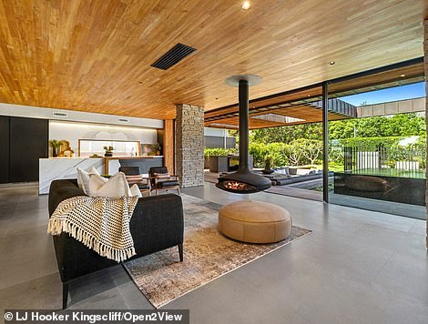 The dining room in the open-plan family room looks out onto the fish pond through glass folding doors and the teak ceilings and stone pillars add earthy natural textures.