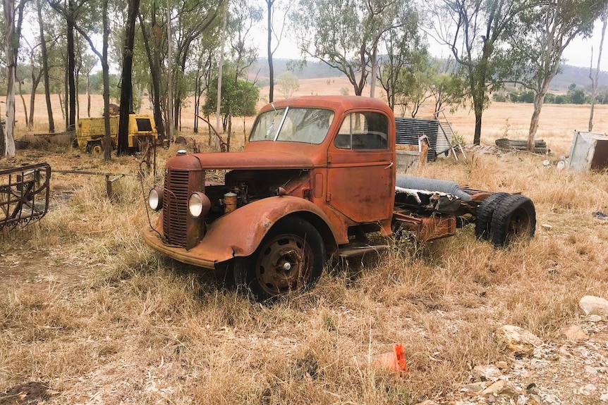 A rusty truck parked on a rural property.