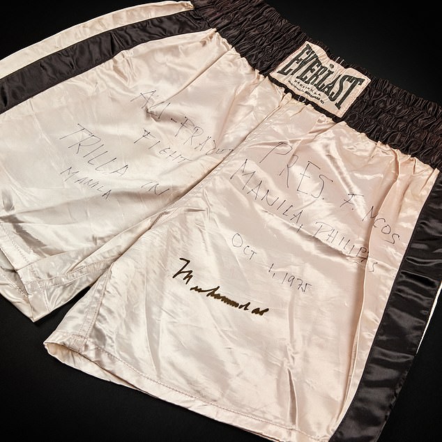 The Everlast silk shorts, pure white except for a black belt line and black racing stripes down each leg, are signed Ali.