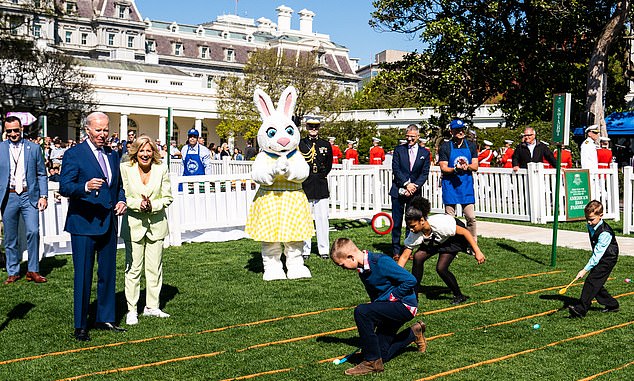 A life-sized Easter Bunny stands near President Joe Biden and First Lady Jill Biden, who are seen laughing as they watch children participate in the Easter roll.