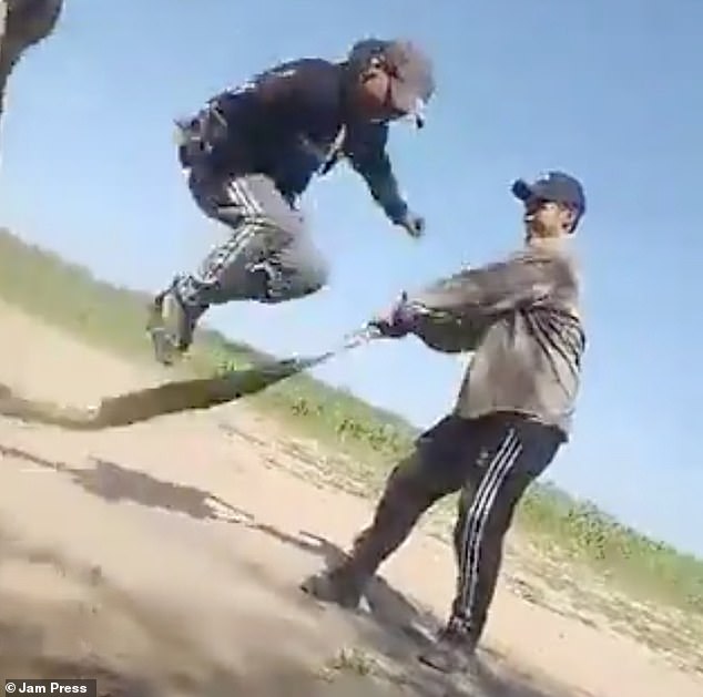 Two of the unidentified men were seen grabbing the huge boa constrictor by the neck and tail, while a third man stood between them on a dirt road in the Argentinian countryside.